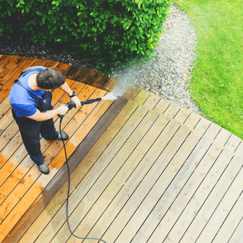 Pressure washing wooden deck outdoors